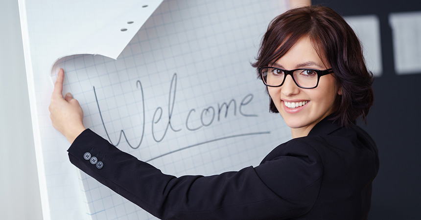 Eine Mitarbeiterin schreibt „Welcome“ auf das Flipchart.